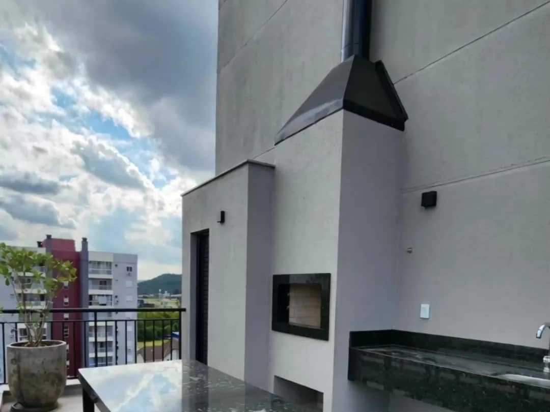 Terraço do Campus Studios II, com lareira, churrasqueira e vista para a cidade.