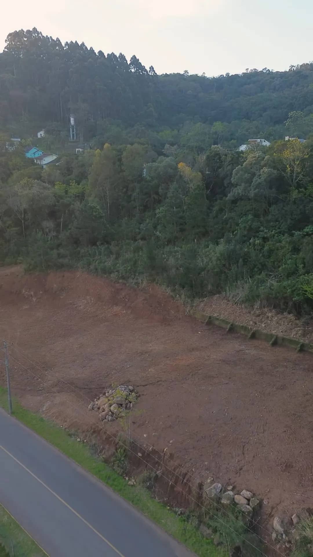 A área limpa do terreno, com a mata e o morro ao fundo.