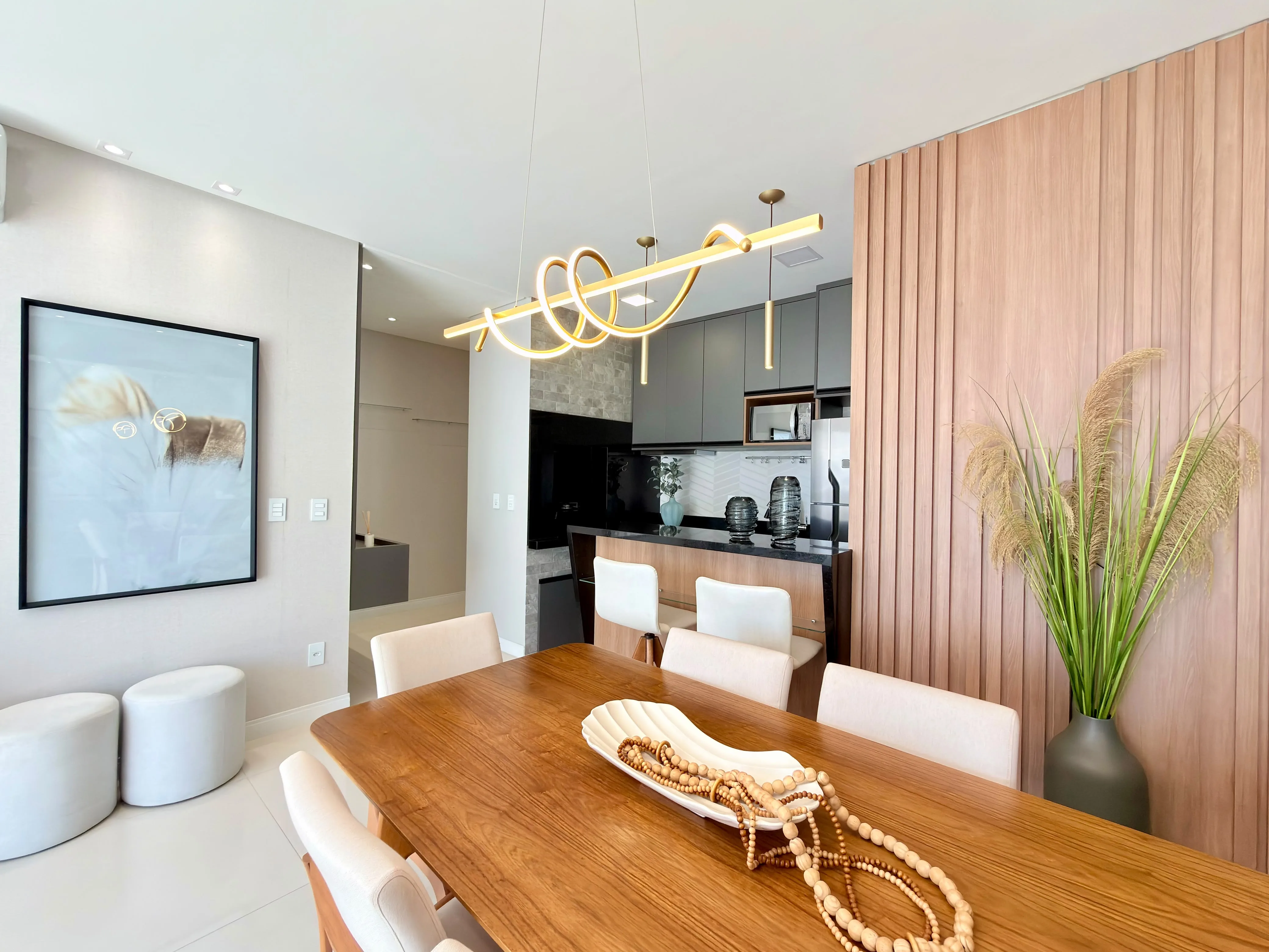 Sala de jantar com mesa para seis lugares e cozinha americana ao fundo