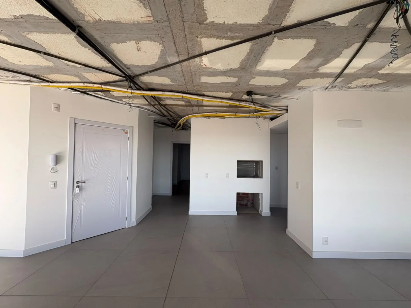 Churrasqueira embutida na parede, porta de entrada e interfone, unidade em obra.