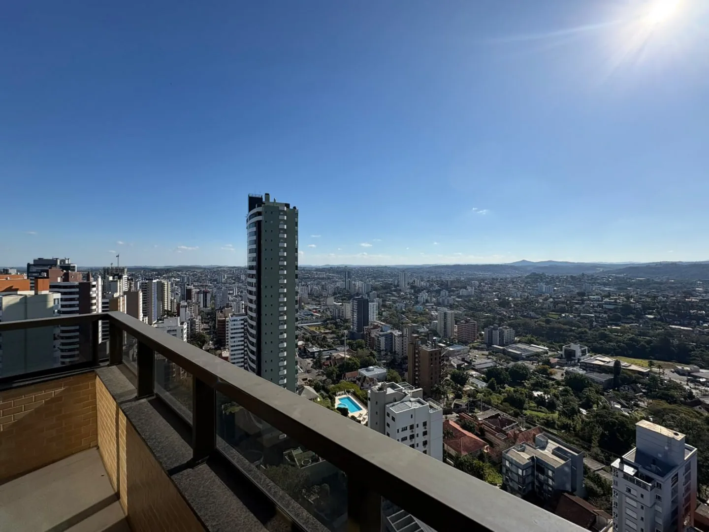 Vista da cidade a partir da sacada, com prédios e morros no horizonte.