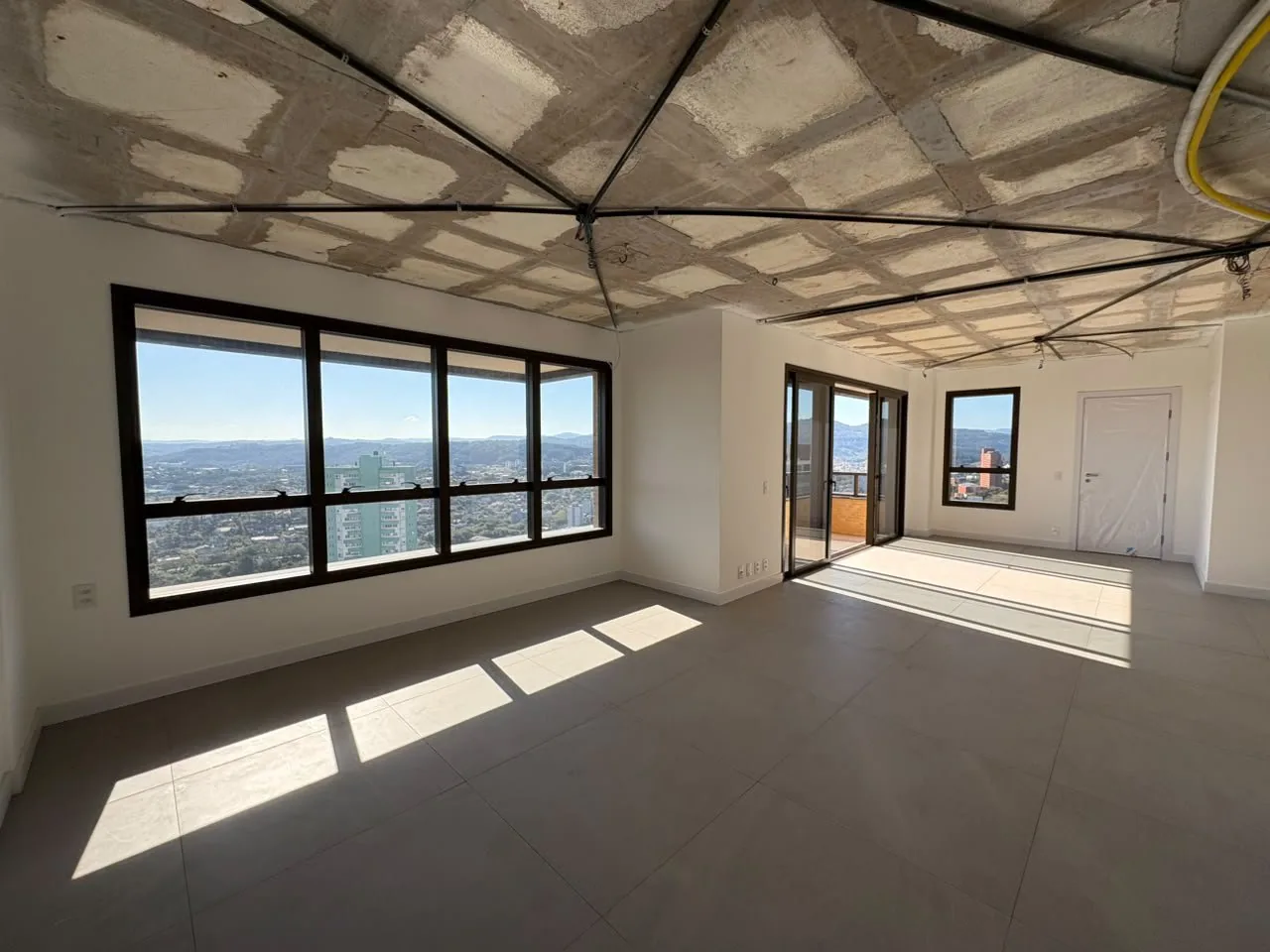 Sala em acabamento, com janela ampla voltada para a cidade.
