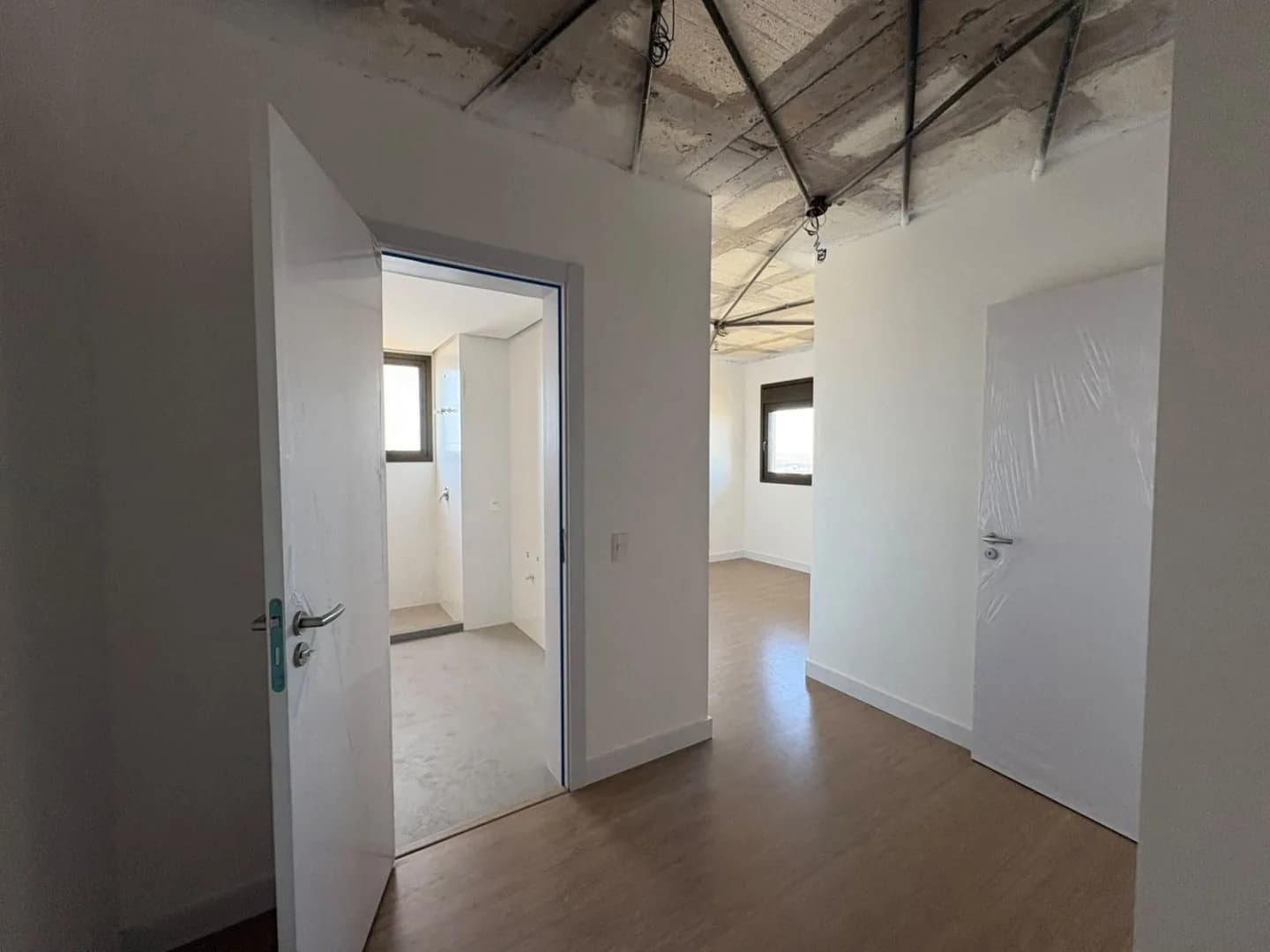 Circulação com portas dos dormitórios e banheiro em acabamento.