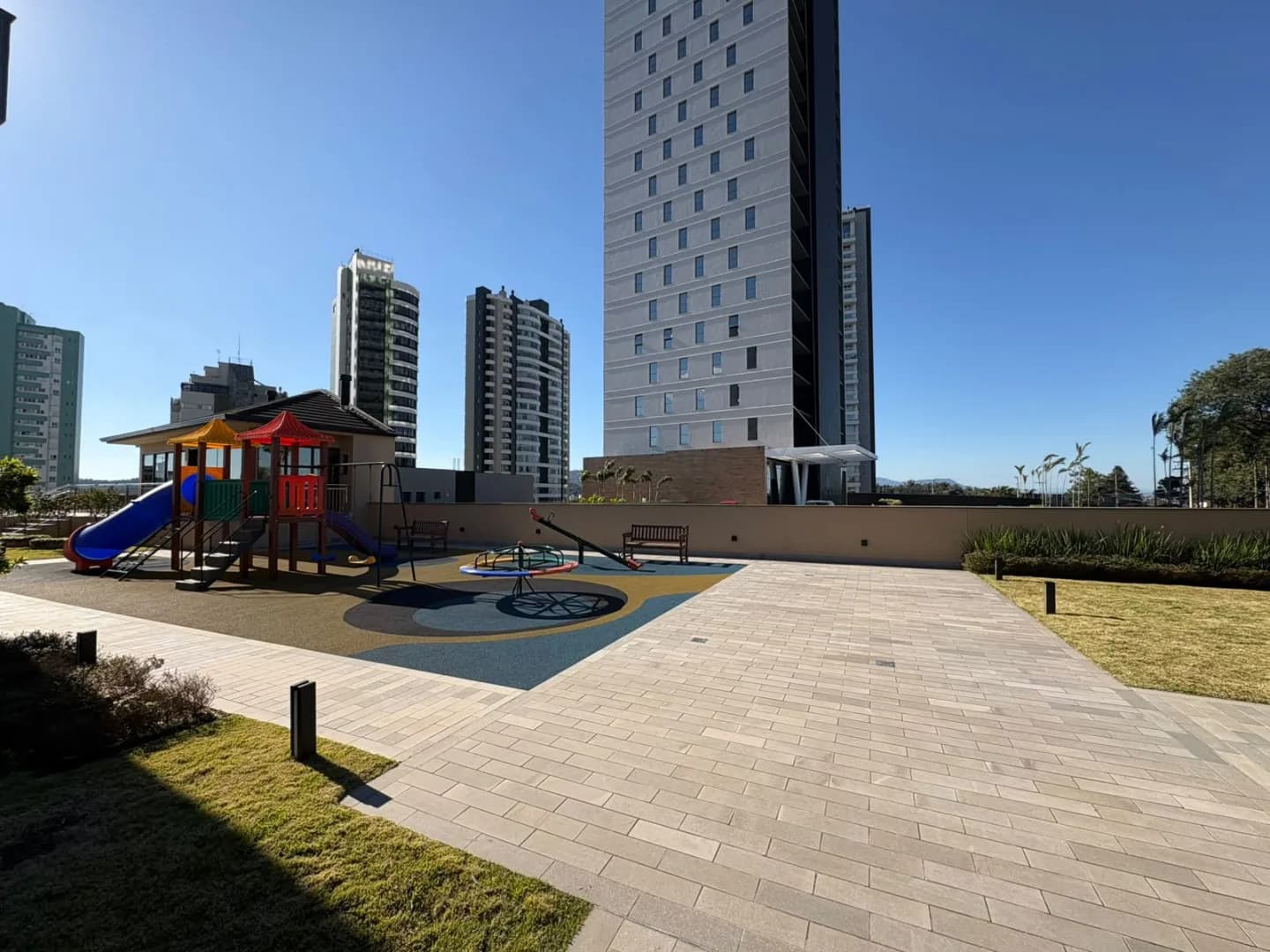 Playground com brinquedos, bancos e piso emborrachado.