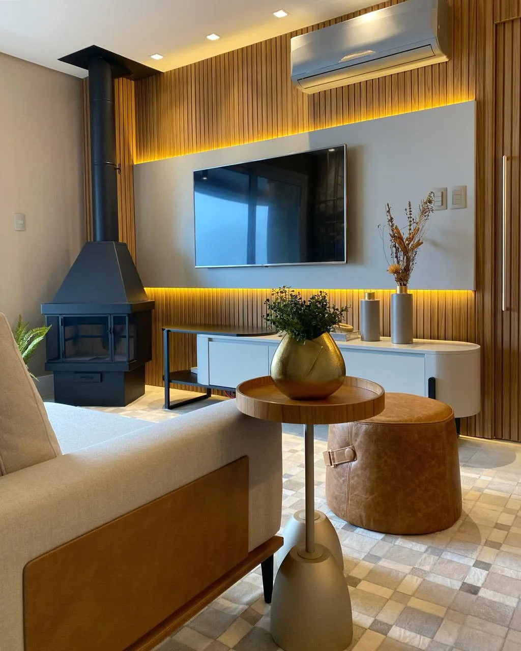 Living com lareira a lenha, TV e mesa de apoio.