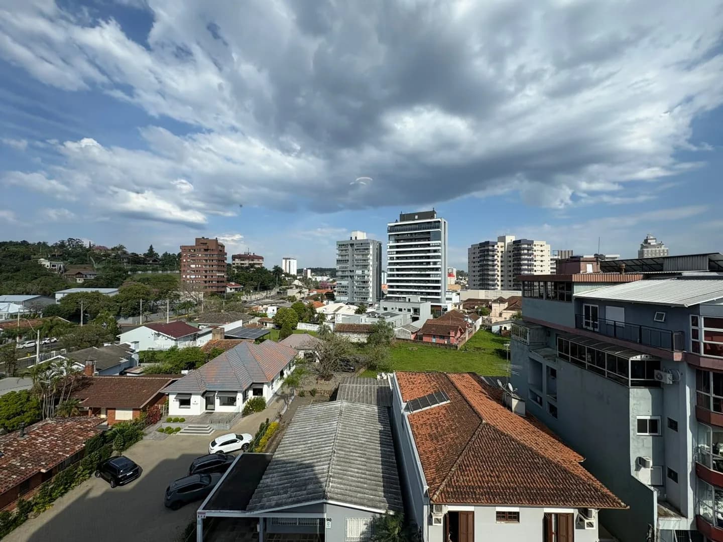 Vista da janela para casas, prédios e morros ao fundo.