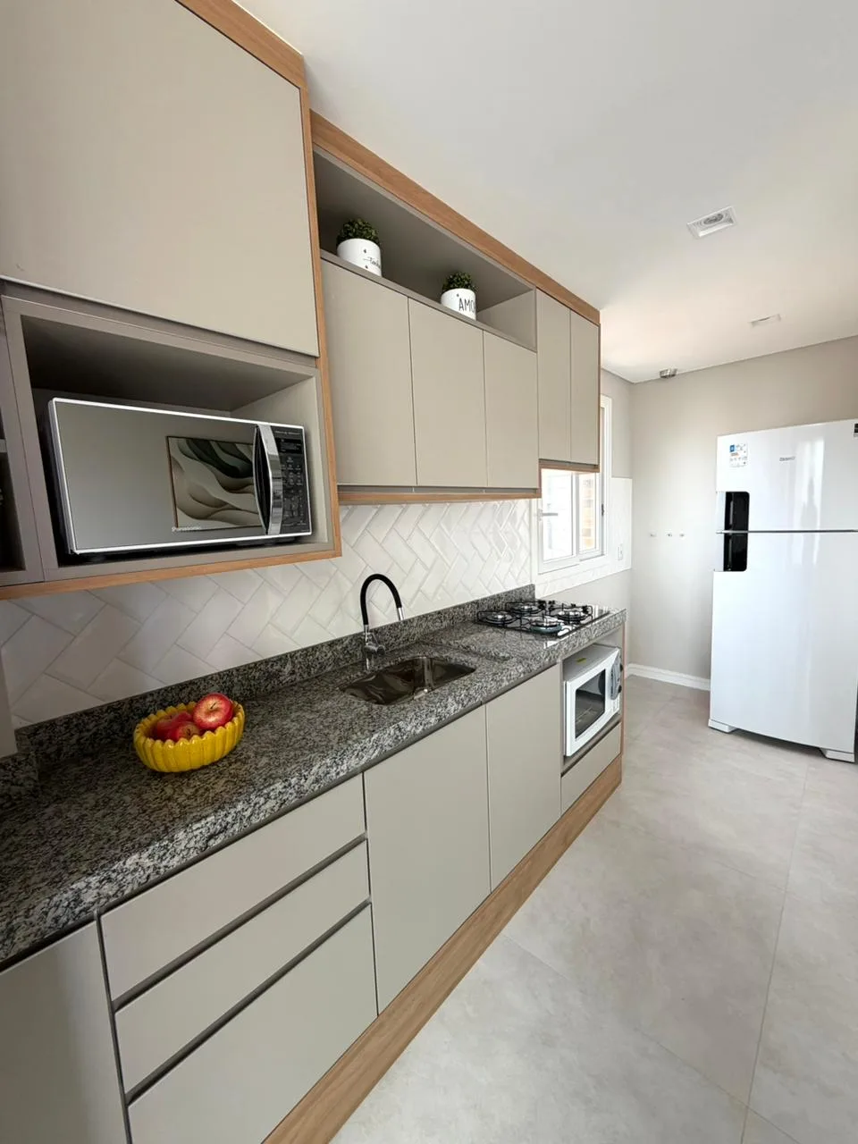 Cozinha americana com cooktop, forno e geladeira