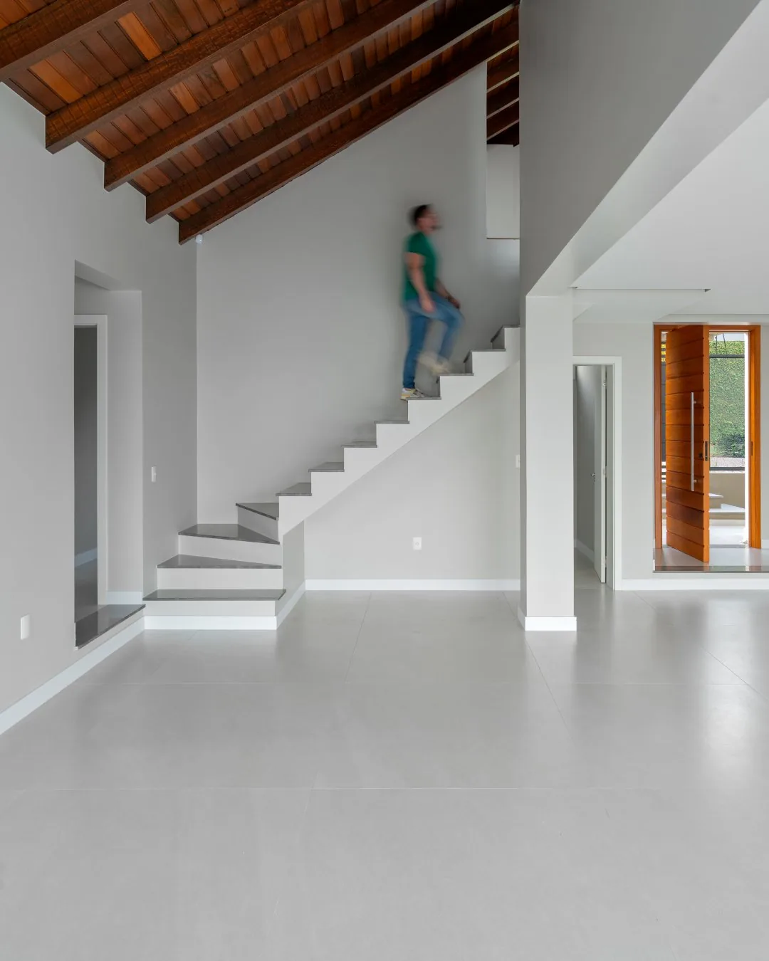Sala vazia com escada e telhado de madeira aparente.