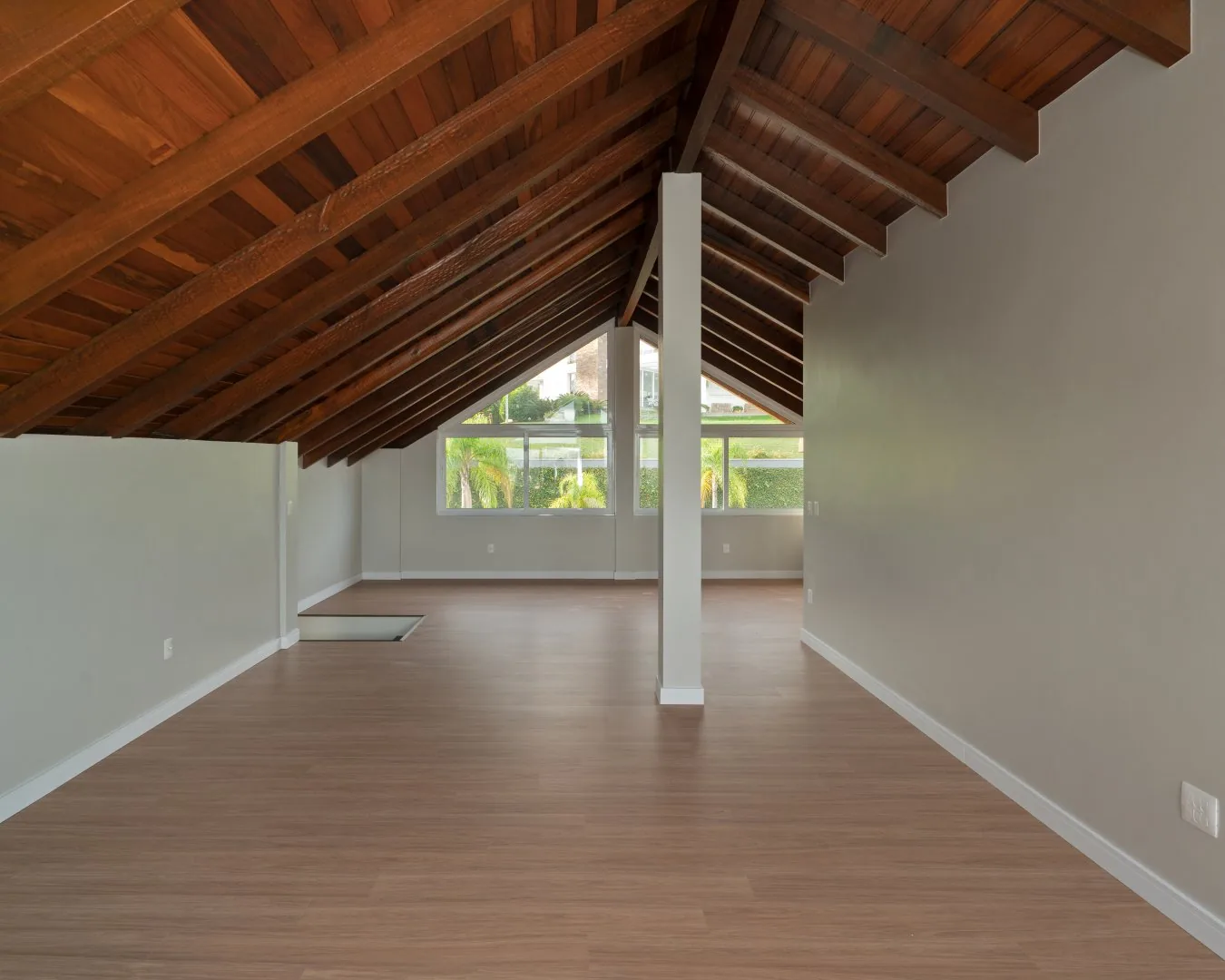 Mezanino com telhado de madeira aparente e piso laminado.