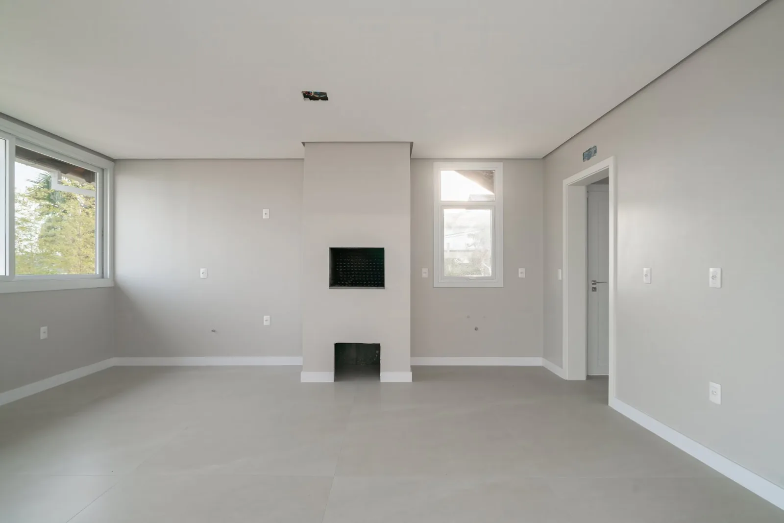 Sala vazia com lareira embutida e duas janelas.