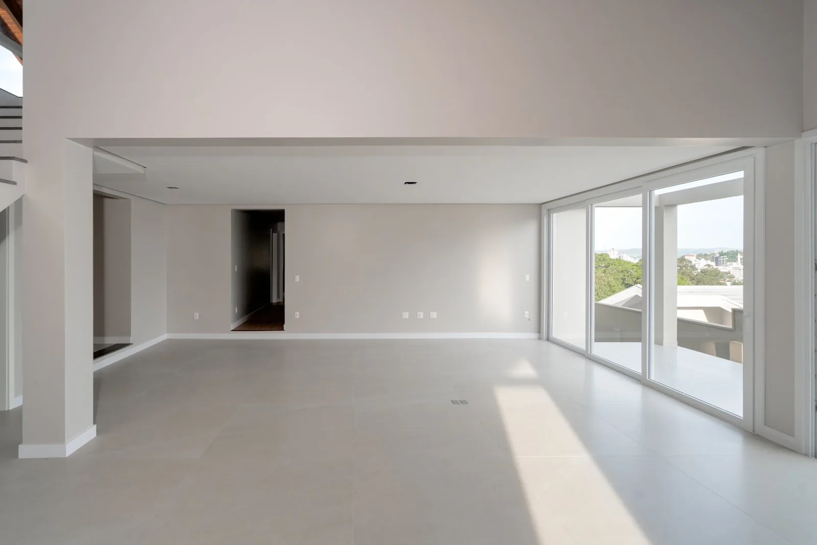 Sala vazia com portas de vidro e vista para a cidade.