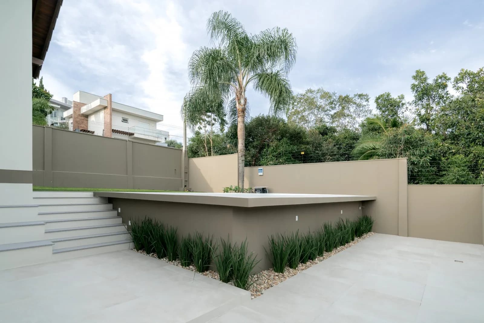 Deck elevado da piscina com escada e canteiro de pedras.