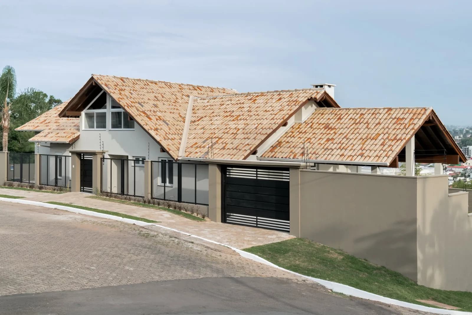 Fachada de esquina com telhado colonial, muro alto e portão de garagem.
