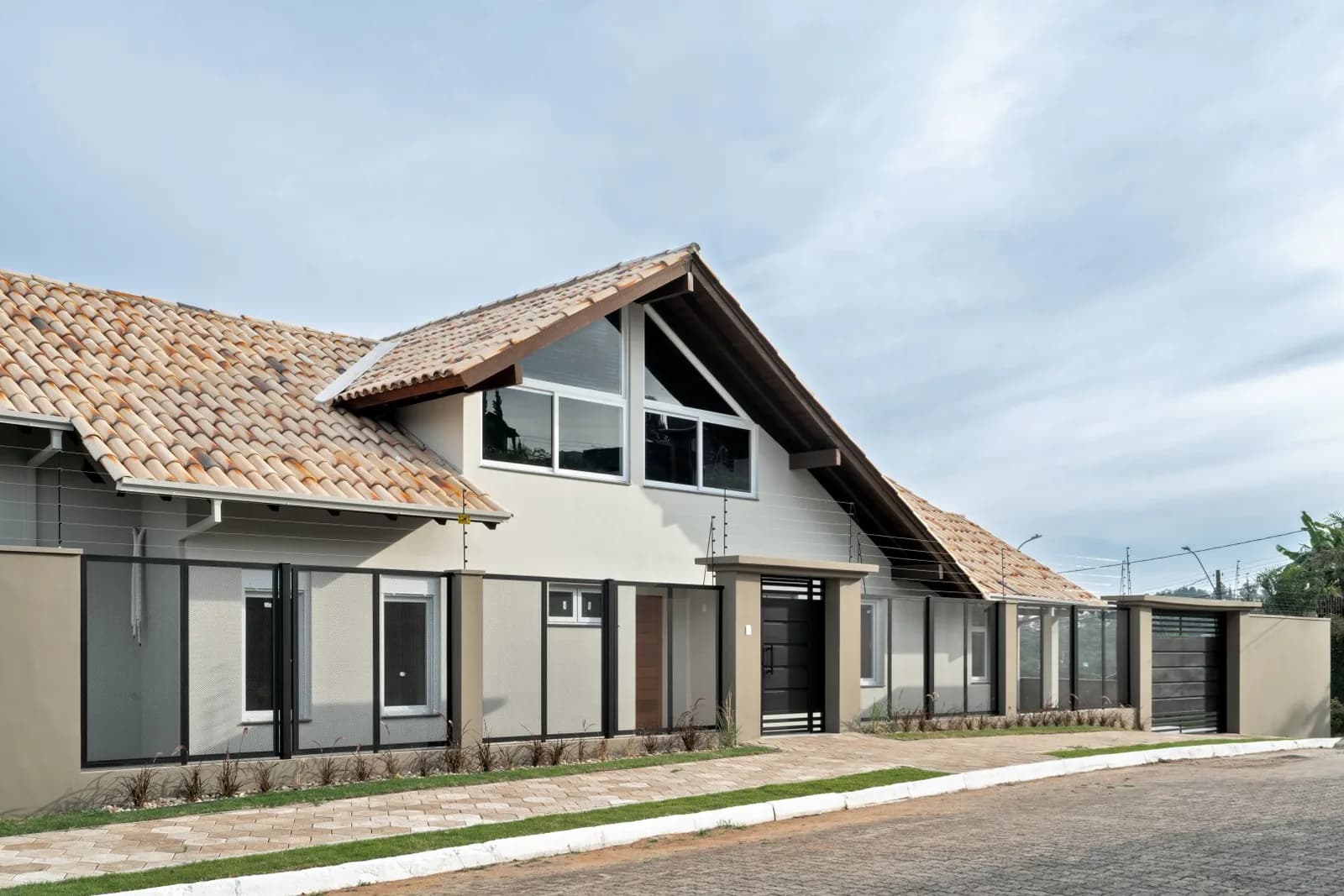 Fachada em perspectiva com muro, grades e portão de garagem.