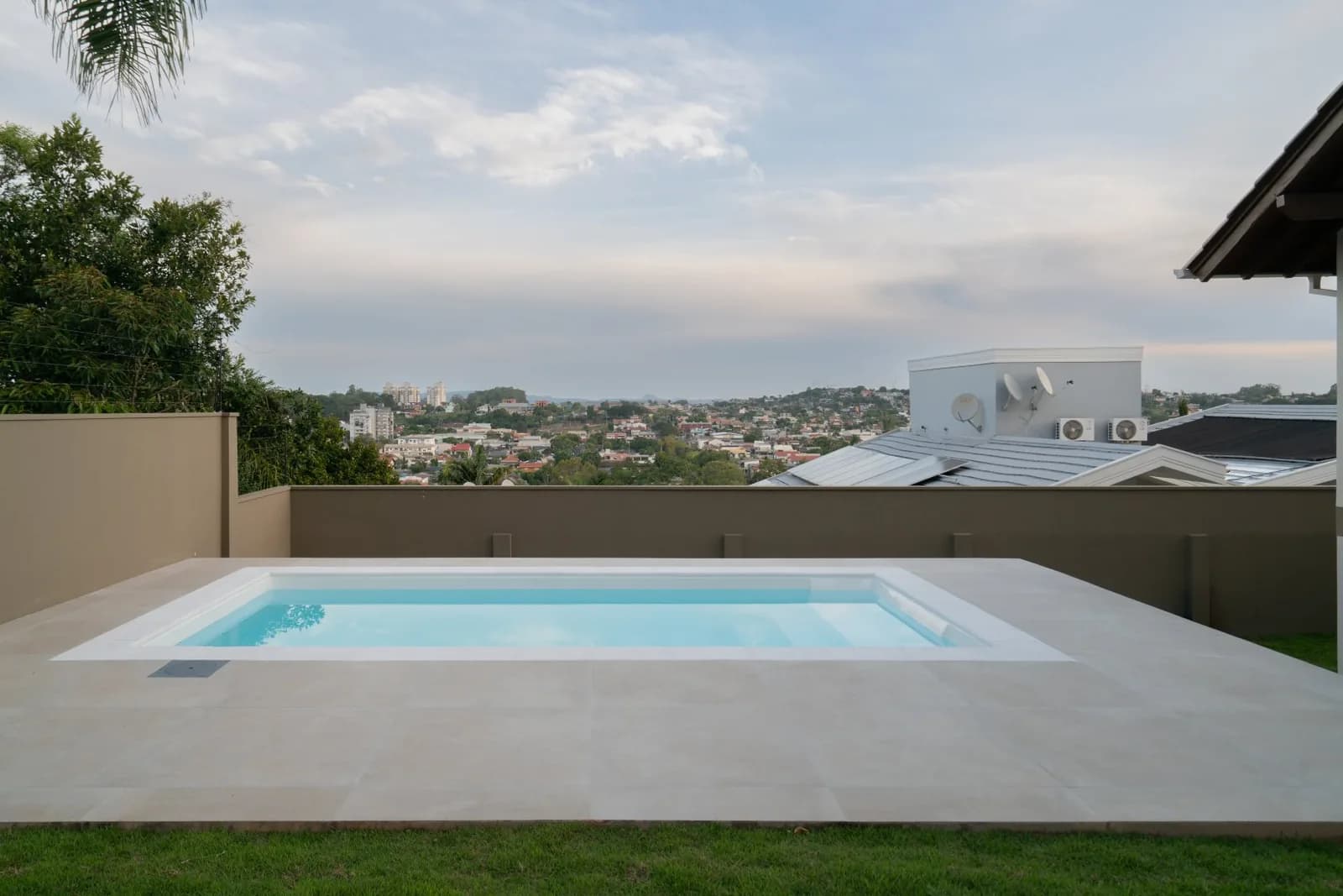 Piscina com deck e vista da cidade ao fundo.