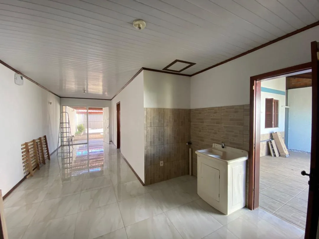 Área de serviço vazia com tanque de louça e azulejo na parede.