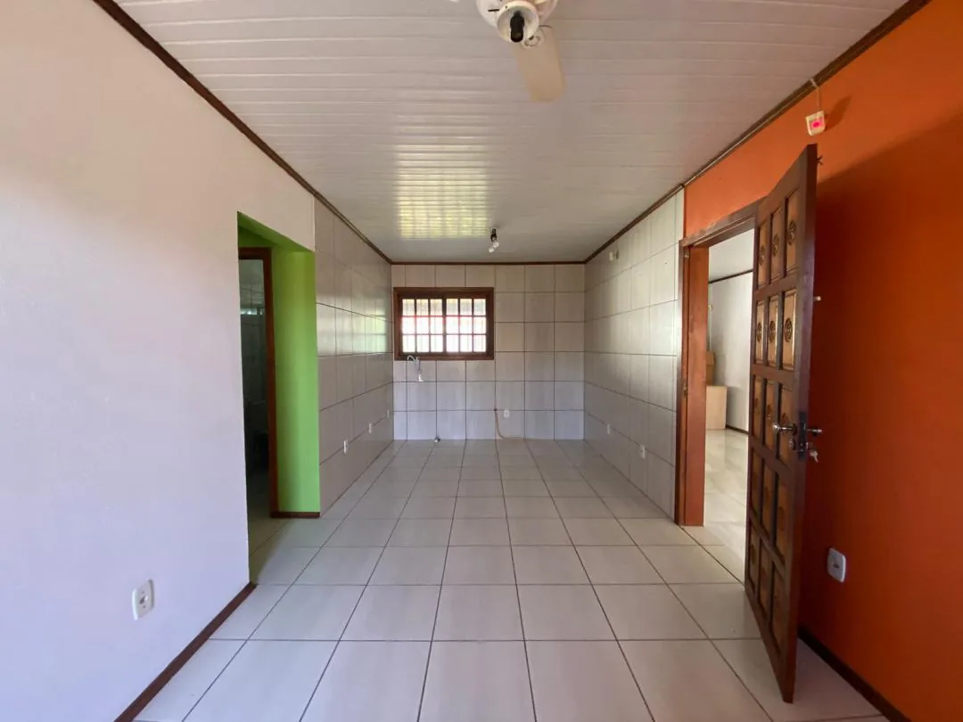 Cozinha vazia com azulejo branco, torneira e janela de madeira.