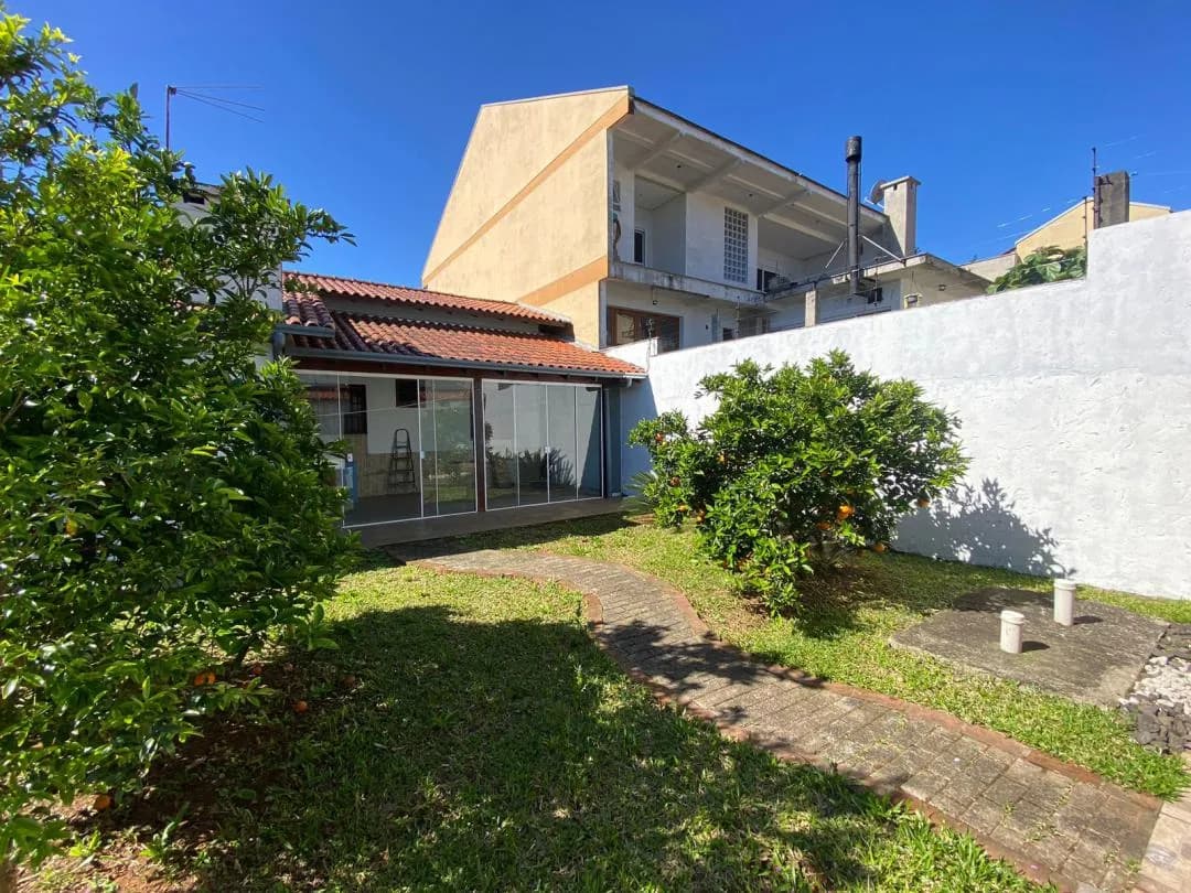 Área envidraçada da casa vista do gramado com laranjeiras.
