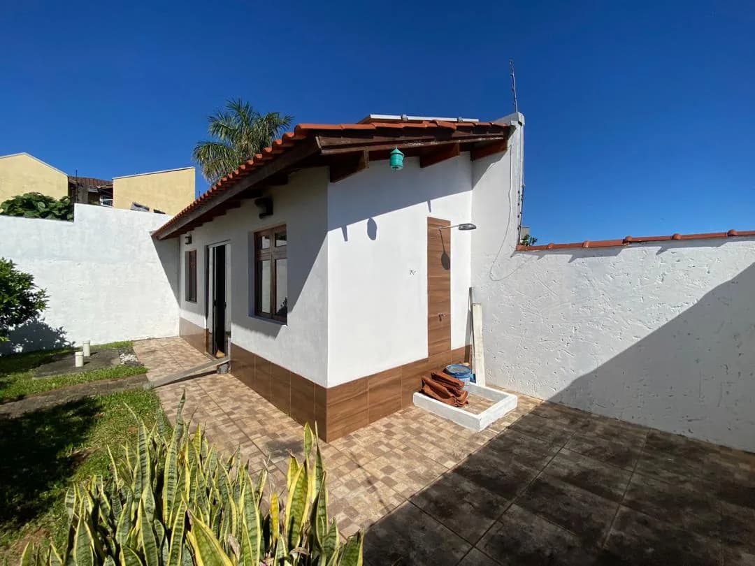 Casa menor nos fundos com porta e janela de madeira e piso cerâmico.