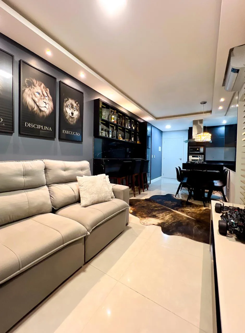 Sala de estar do LG67, com sofá cinza, tapete de pelo e quadros decorativos na parede.
