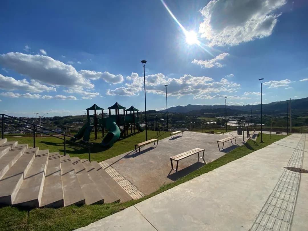 Praça com playground e bancos, no alto do terreno.