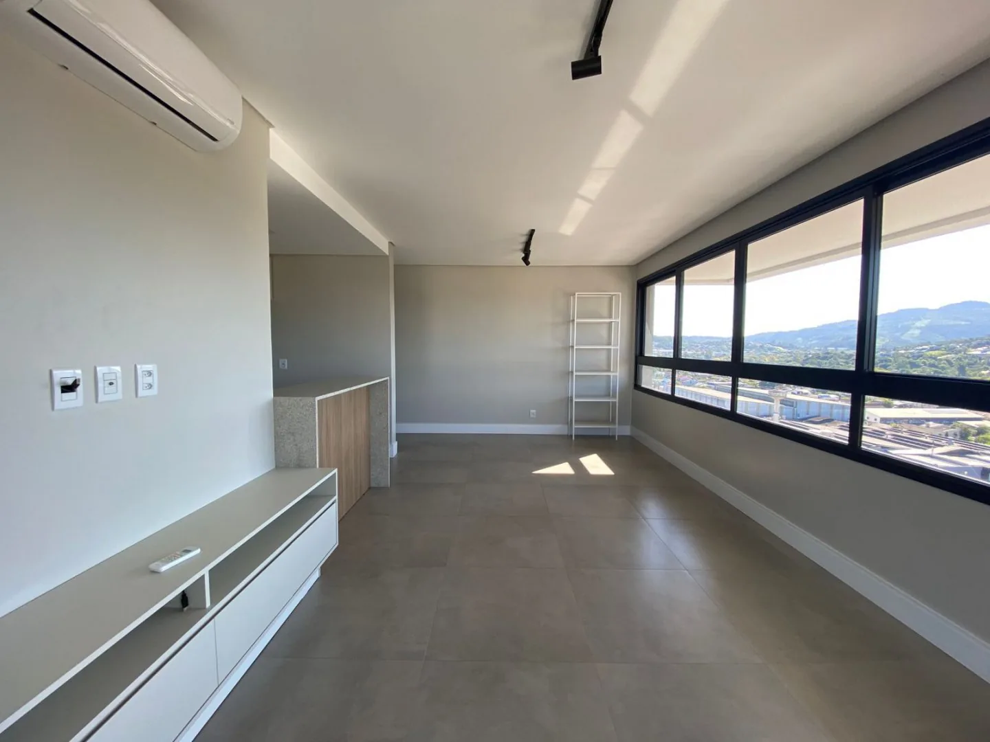 Living do apartamento, com janelas amplas.