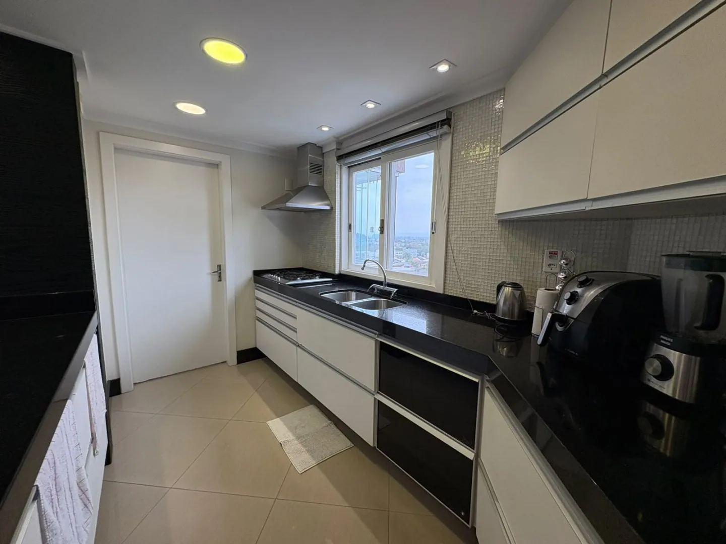 Cozinha com forno embutido e armários claros.
