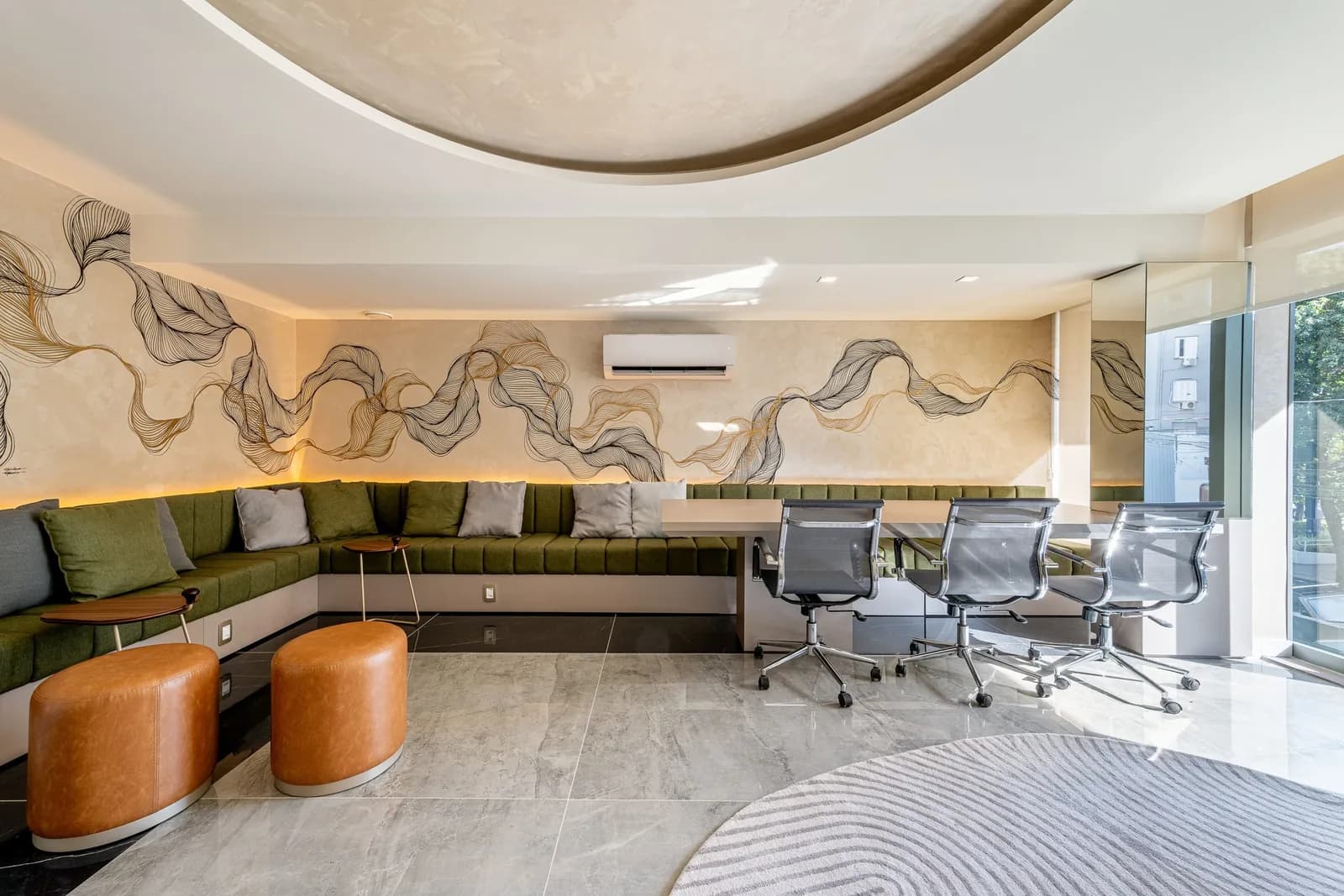 Coworking com mesa de reunião, poltronas e painel gráfico na parede.