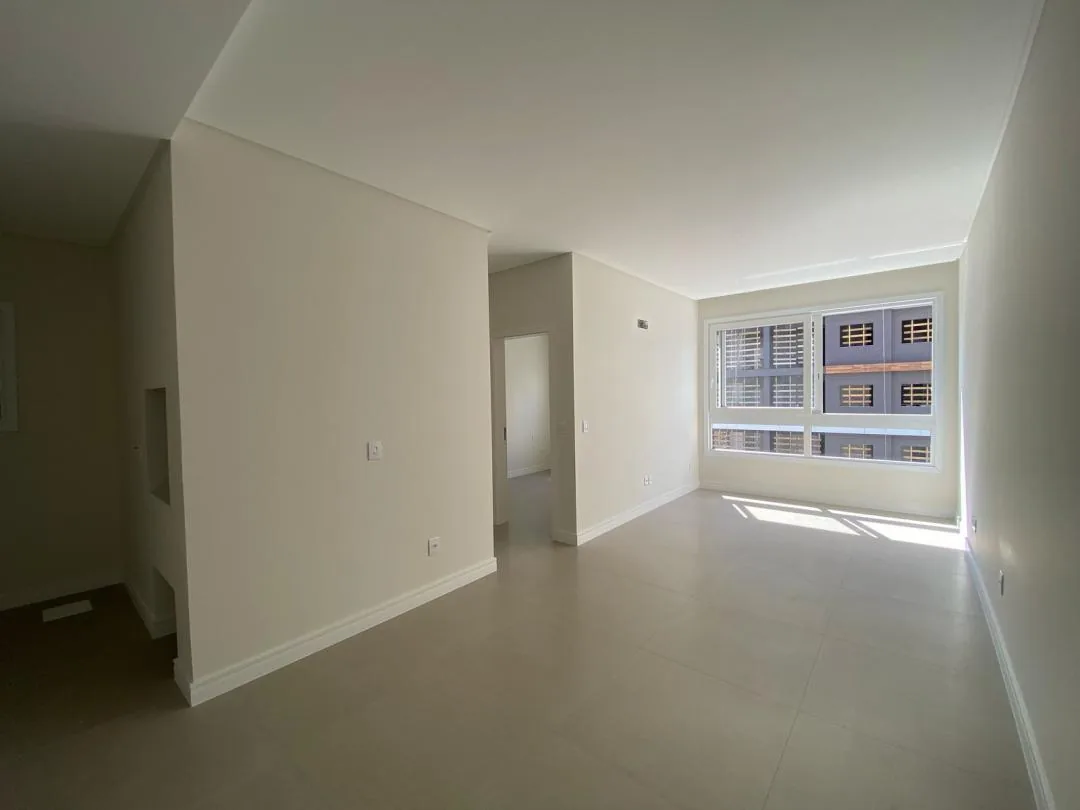 Sala vazia com janela ampla e passagem para o dormitório.