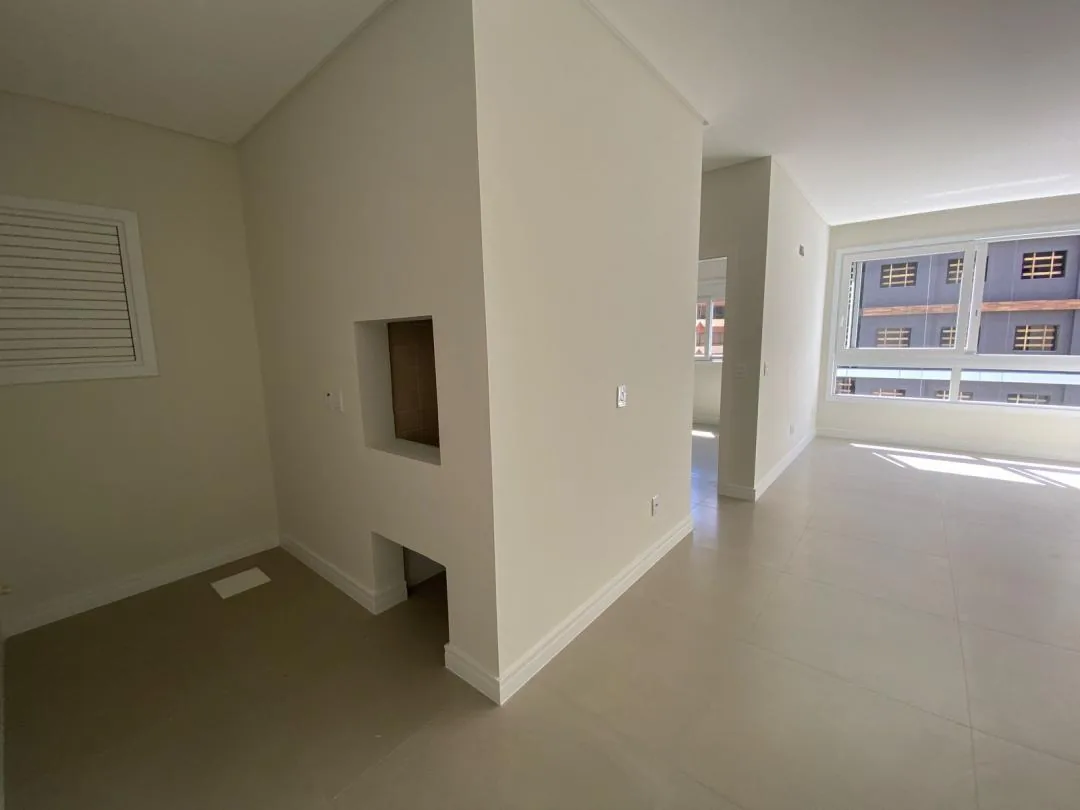 Sala vazia com nicho na parede e janela voltada para prédios vizinhos.