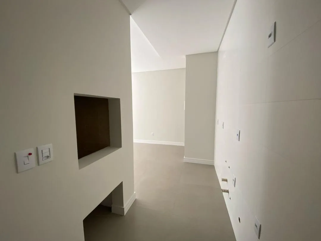 Cozinha vazia com nicho embutido e parede revestida em porcelanato.
