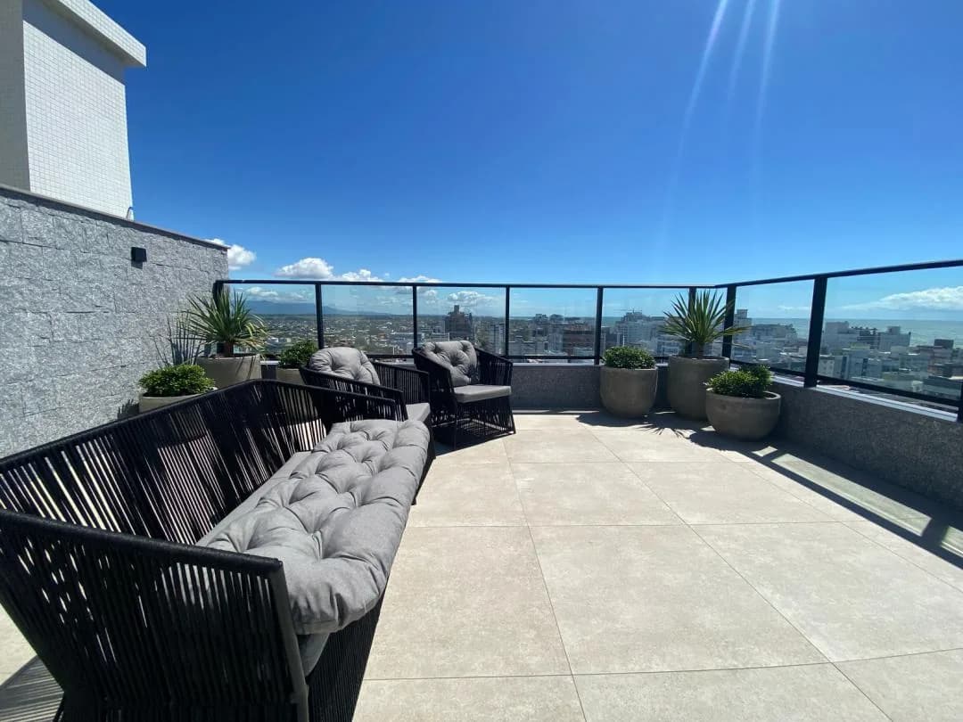 Terraço com sofás de corda, almofadas cinza e vasos de plantas.