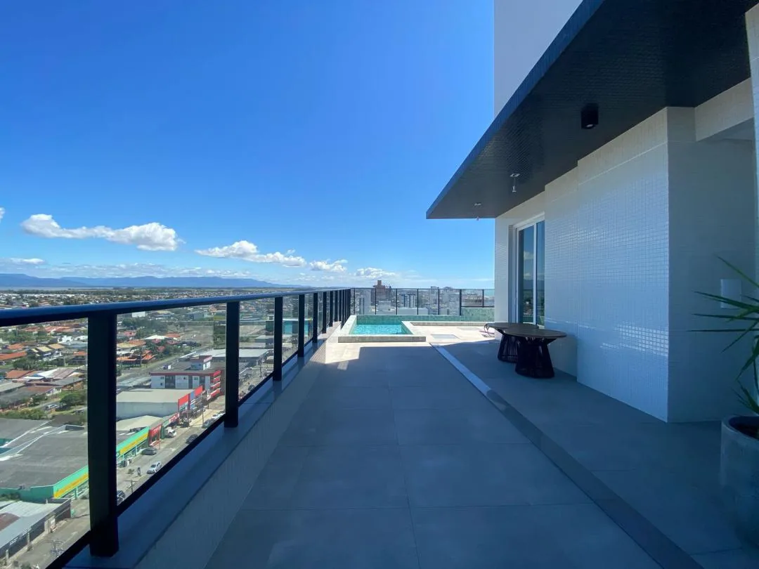 Terraço lateral do rooftop com mesa redonda e piscina ao fundo.