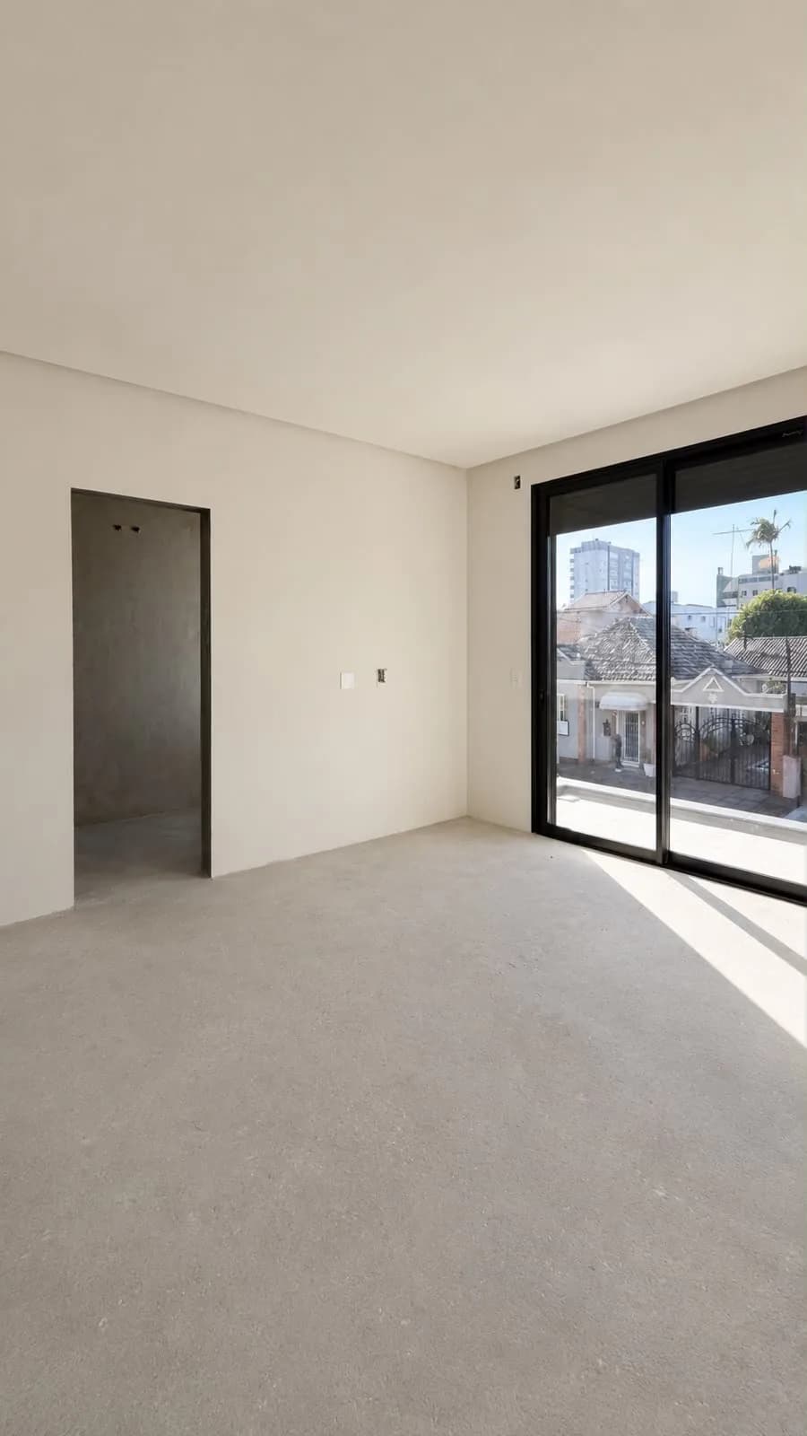 Quarto sem acabamento, com porta de correr para a sacada.