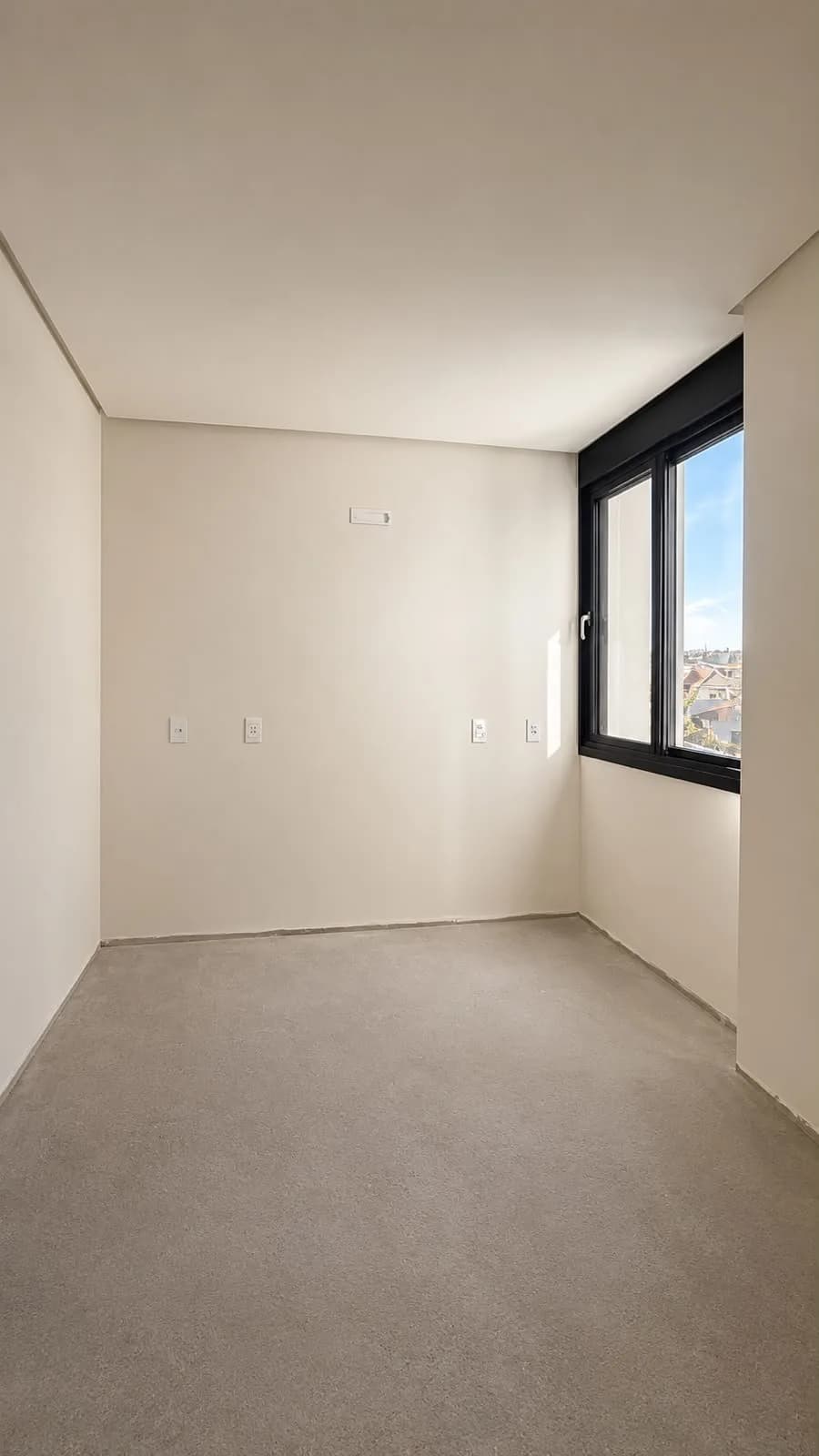Quarto sem acabamento, com janela de alumínio preta no canto.