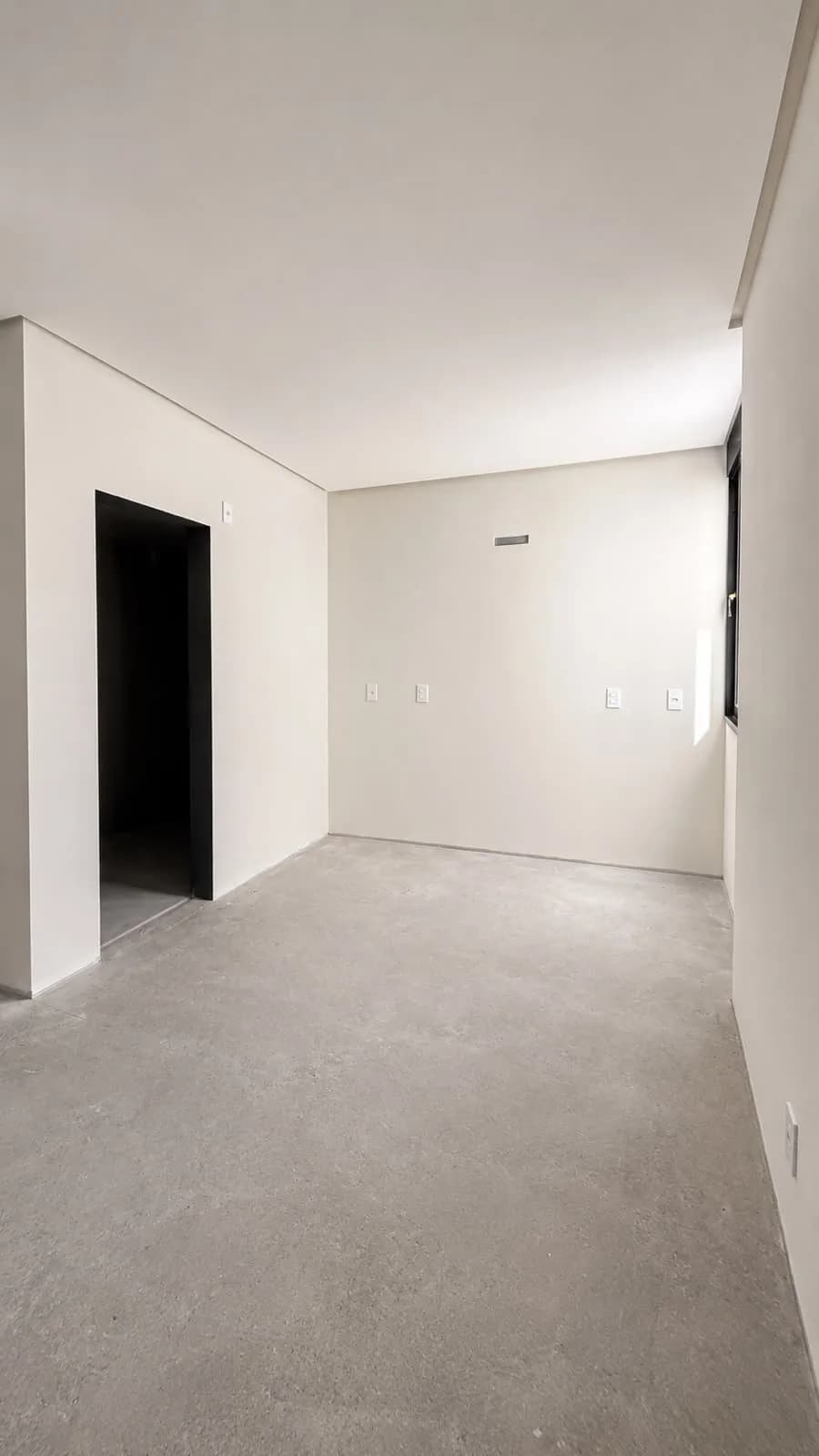 Quarto sem acabamento no piso, com vão de porta sem esquadria.