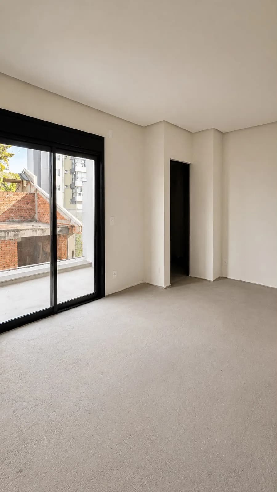 Quarto sem acabamento, com porta de correr e vista para a rua.