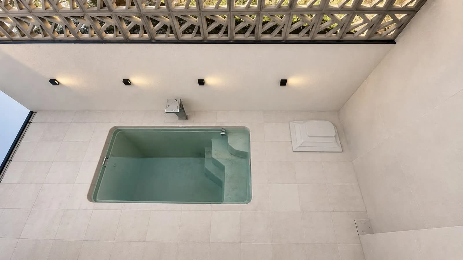 Piscina no pátio interno, com piso porcelanato e parede de cobogó.