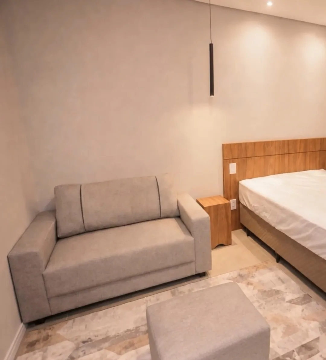 Interior de studio mobiliado, com bancada de trabalho, cama e armário embutido.
