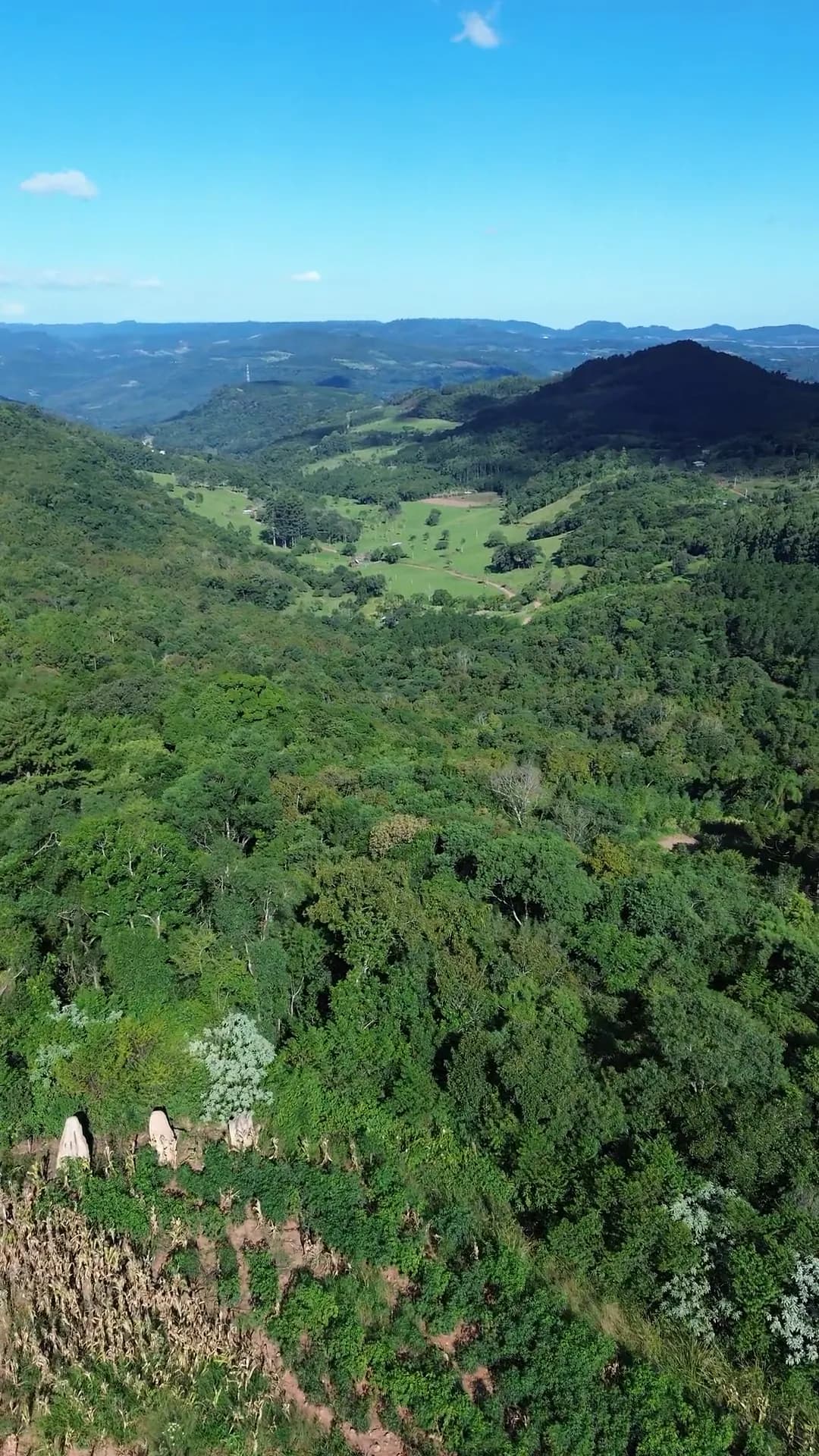 Vale e coxilhas da Serra Gaúcha vistos do alto, com um morro ao fundo.