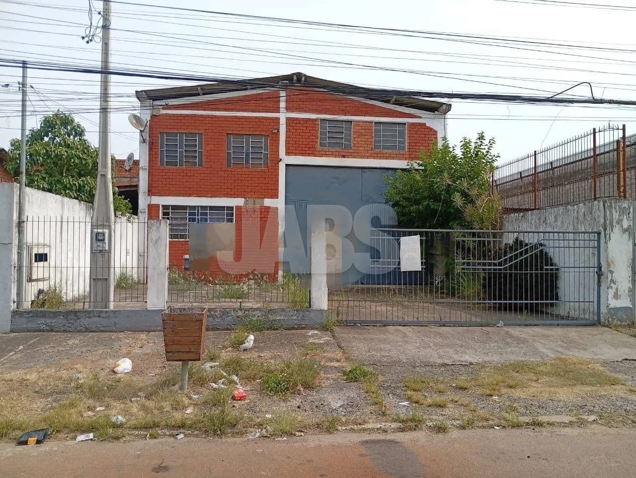 Fachada do pavilhão com portão e muro, na rua do bairro Niterói
