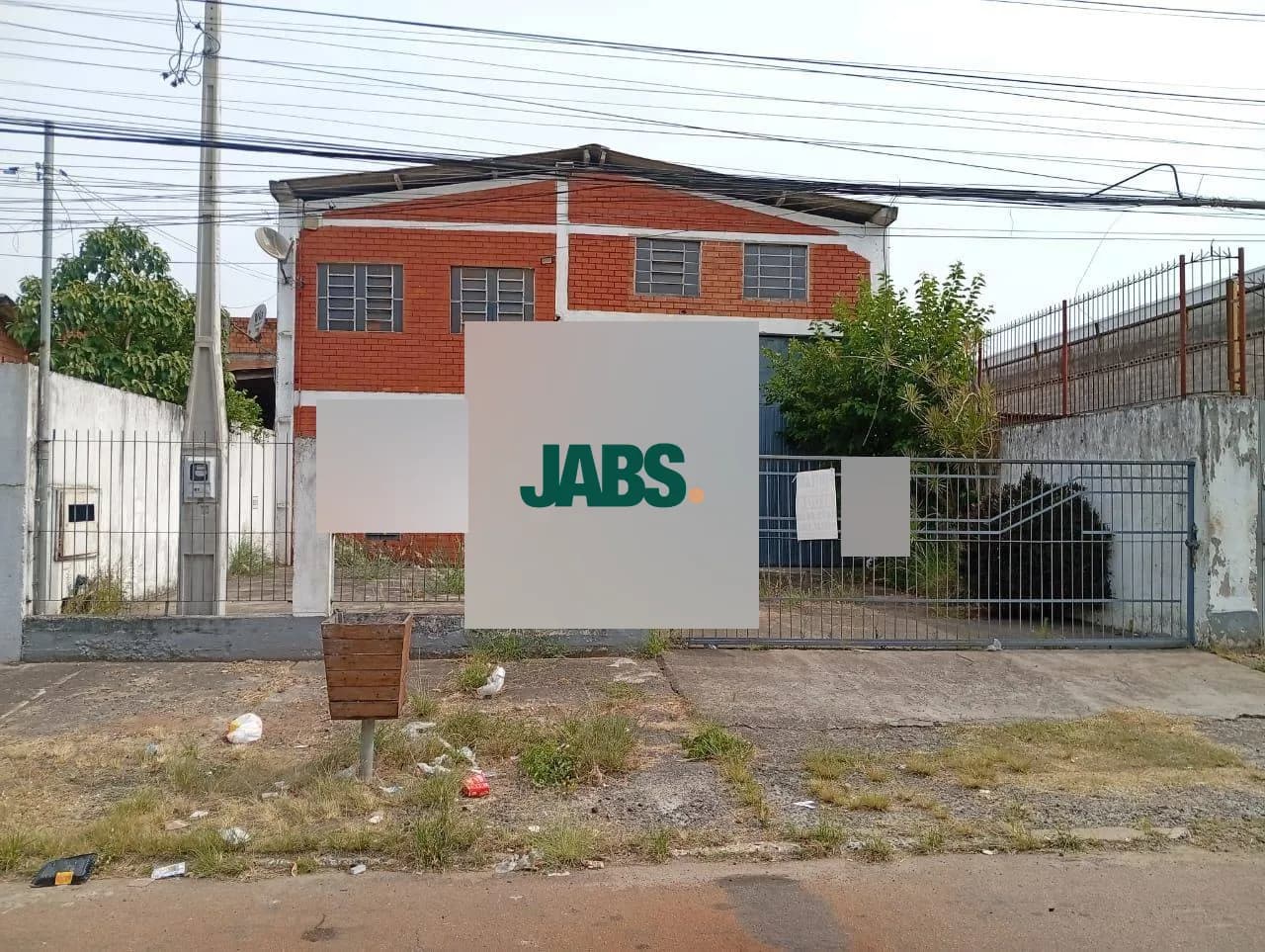 Fachada do pavilhão com portão e muro, na rua do bairro Niterói