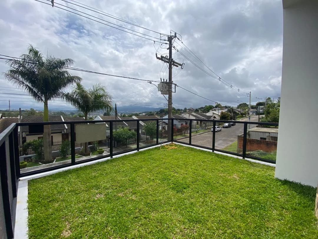Gramado frontal com guarda-corpo de caixilho preto e vista elevada para a rua e o bairro