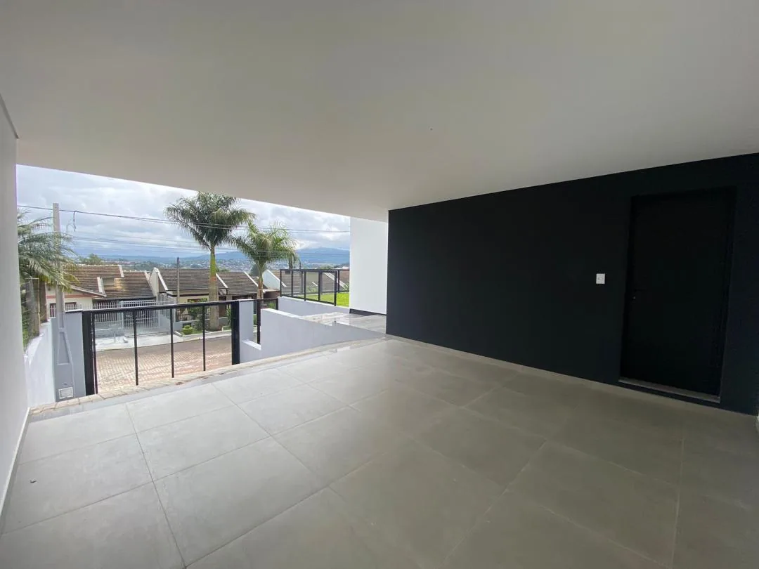 Garagem coberta com porcelanato cinza, parede preta com porta e vista para a rua