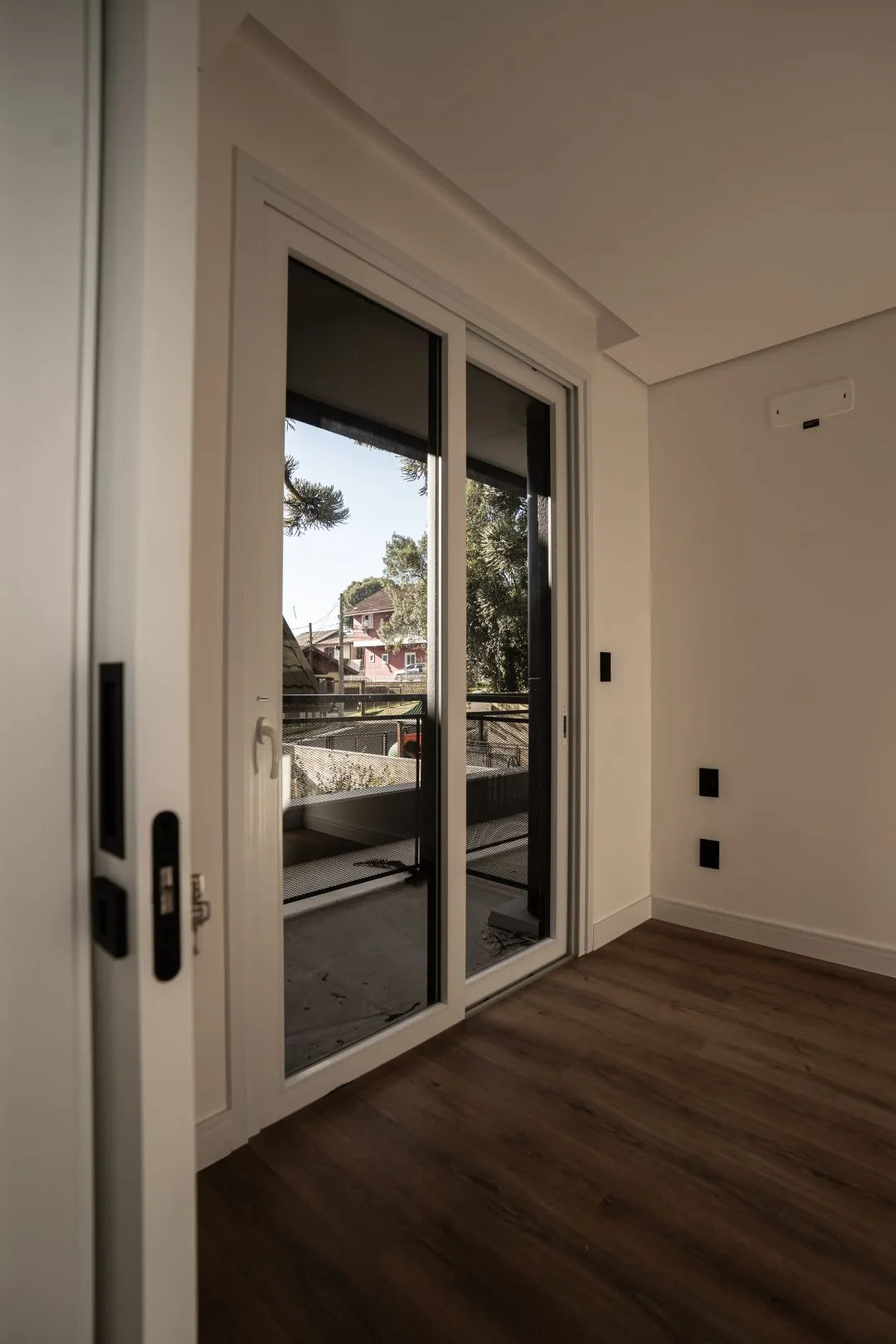Quarto com porta de vidro de correr para a sacada e piso vinílico amadeirado