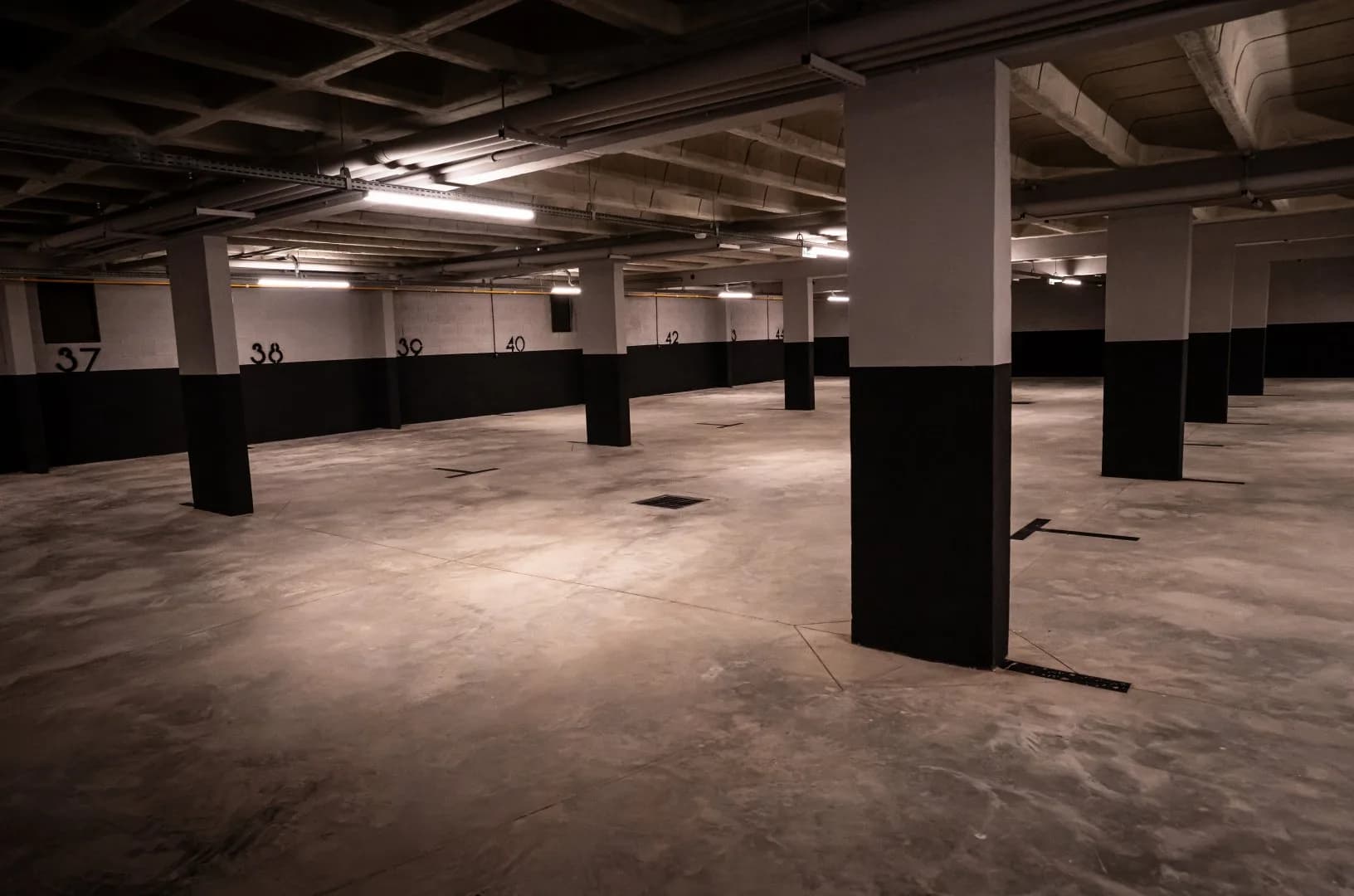 Garagem coberta com vagas numeradas e pilares com a base pintada de preto