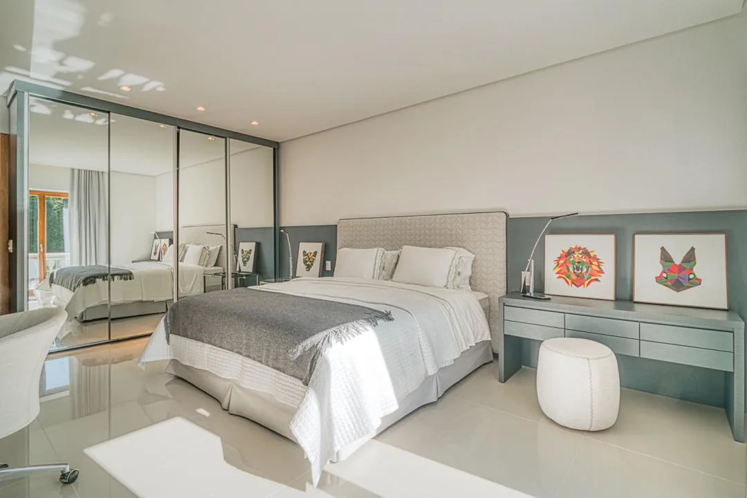 Suíte com armário de portas espelhadas, cama de casal, penteadeira com pufe e quadros coloridos de animais