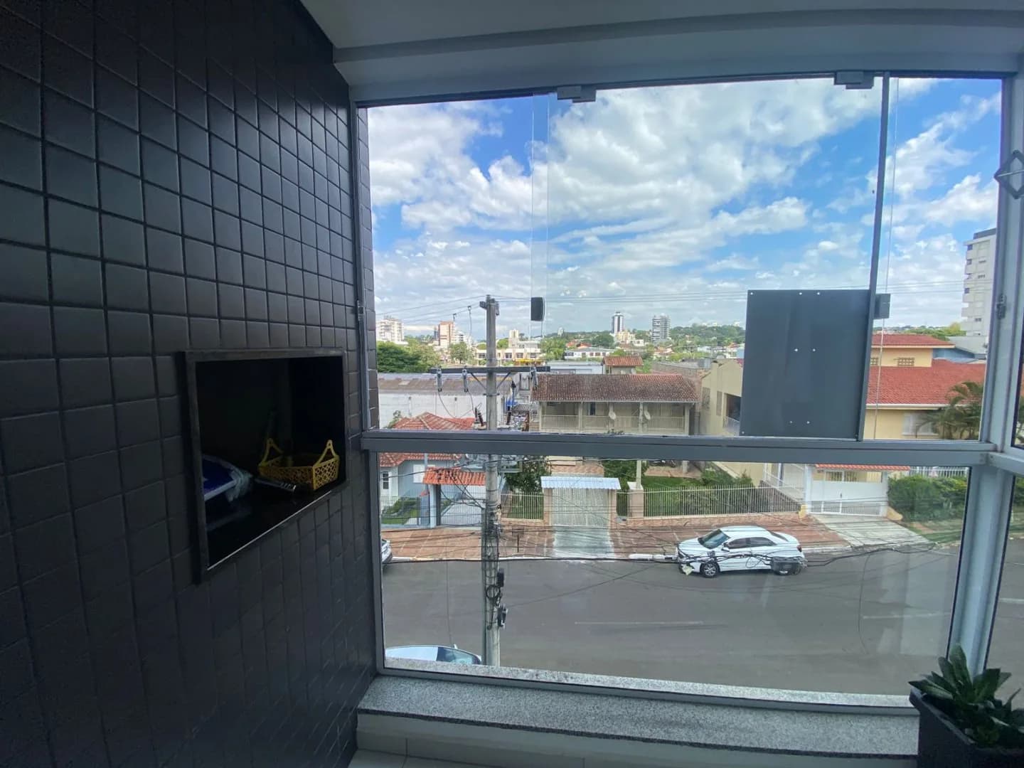 Sacada envidraçada com parede de pastilhas pretas e nicho embutido, com vista para a rua