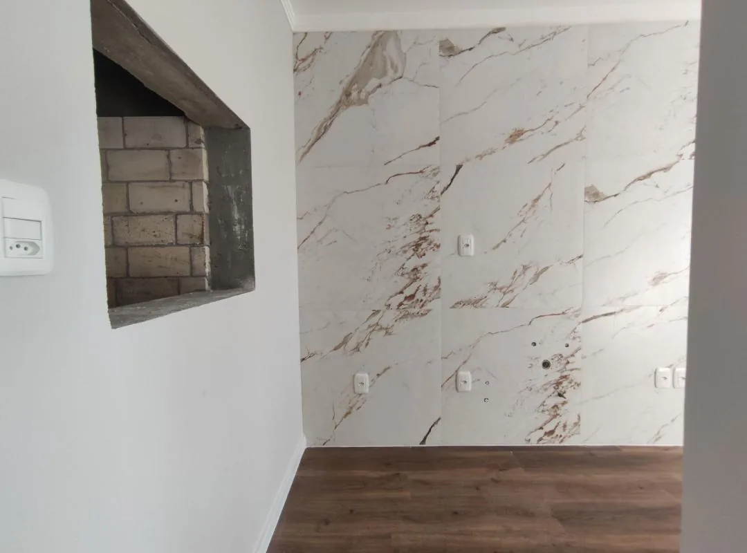 Nicho revestido de tijolos aparentes ao lado da parede da cozinha em porcelanato marmorizado