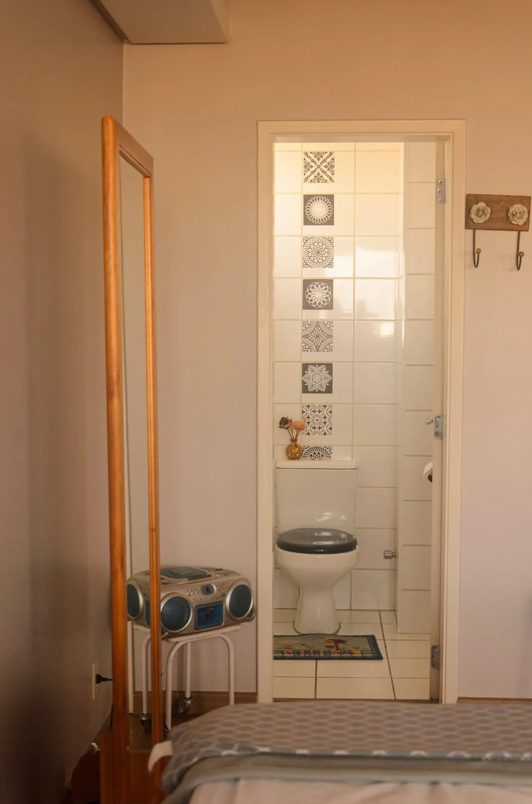 Banheiro com vaso sanitário e faixa de azulejos decorados, visto a partir da sala